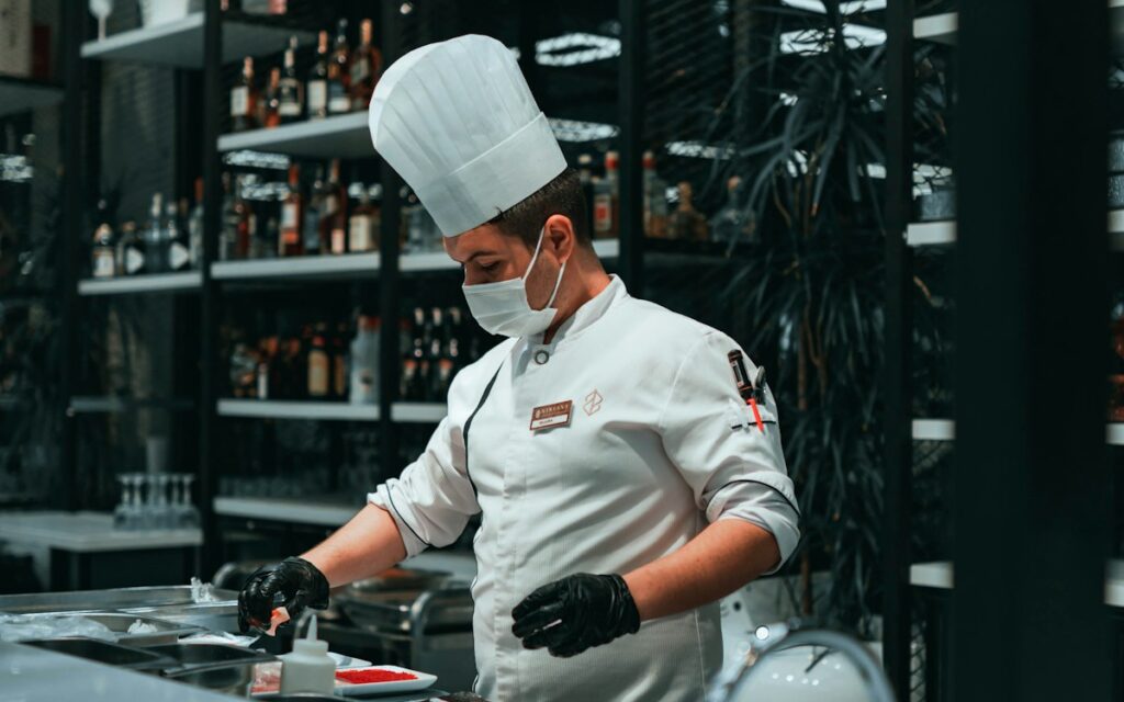 Chef wearing gloves and a face mask while preparing food