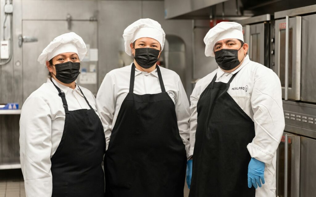 Team of chefs wearing face masks and aprons