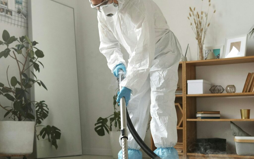 Cleaner in protective gear cleaning a room