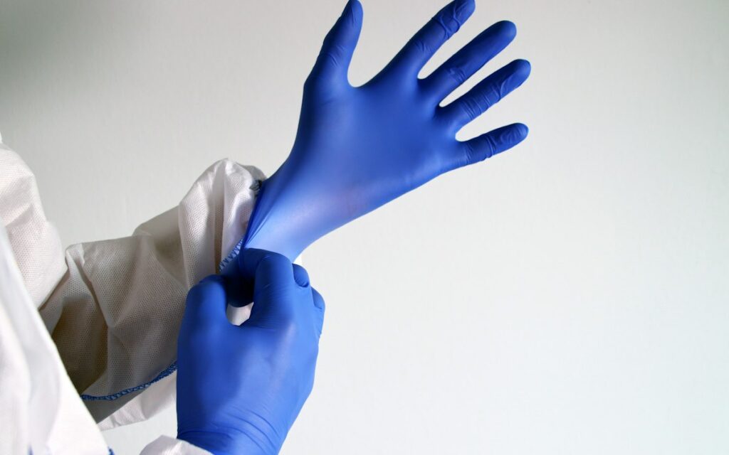Cleaner putting on disposable protective gloves before handling chemicals