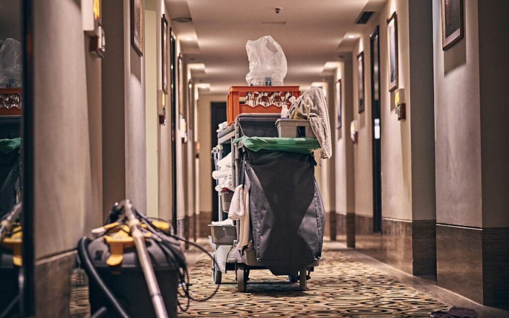 Cleaner pushing a cleaning trolley along a corridor